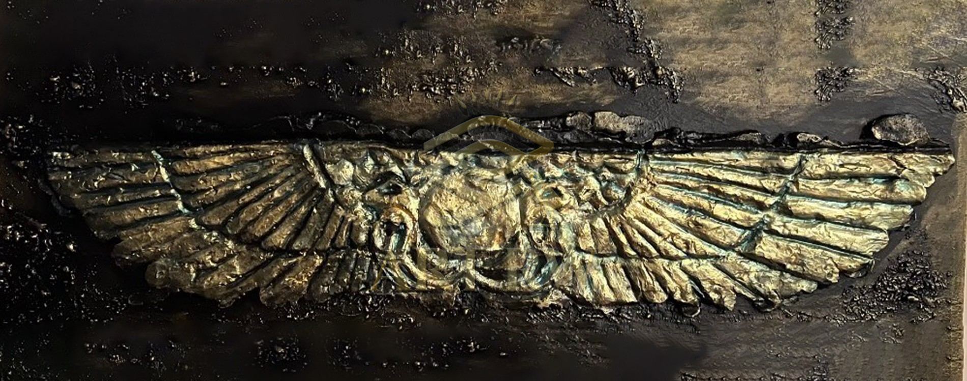 Metallic artwork showing a double-winged ancient-style emblem with detailed texture and central circular design on a dark, rough background.